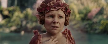 Movie still from “Maleficent” (2014), directed by Robert Stromberg – An older woman wearing a flower crown and a pink dress; Close Up shot, High angle