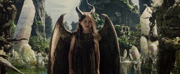 Movie still from “Maleficent” (2014), directed by Robert Stromberg – A young girl in a black dress with a large black angel wings behind her; Medium shot, High angle