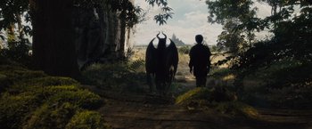 Movie still from “Maleficent” (2014), directed by Robert Stromberg – A man and a cow walking down a dirt road; Wide shot, Low angle