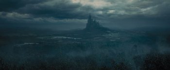 Movie still from “Maleficent” (2014), directed by Robert Stromberg – A castle in the middle of the night with dark clouds; Extreme Wide shot, Low angle