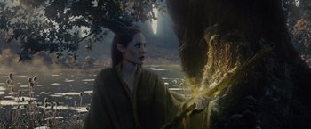 Movie still from “Maleficent” (2014), directed by Robert Stromberg – A woman dressed as maleficent holding a tree branch; Medium shot, Over the shoulder angle