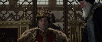 Movie still from “Maleficent” (2014), directed by Robert Stromberg – A man wearing a gold crown and a red robe; Close Up shot, Over the shoulder angle