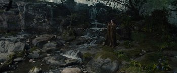 Movie still from “Maleficent” (2014), directed by Robert Stromberg – A woman standing on a rock near a waterfall; Wide shot, High angle