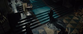 Movie still from “Maleficent” (2014), directed by Robert Stromberg – A man in a black robe and a black cape walking down some steps; Extreme Wide shot, High angle