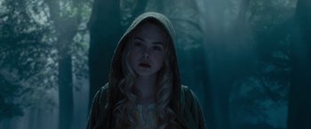 Movie still from “Maleficent” (2014), directed by Robert Stromberg – A young woman in a hooded jacket standing in a forest; Close Up shot, Low angle