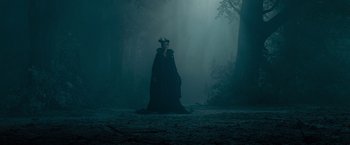 Movie still from “Maleficent” (2014), directed by Robert Stromberg – A woman in a black dress standing in the middle of a forest; Wide shot, Low angle