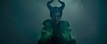 Movie still from “Maleficent” (2014), directed by Robert Stromberg – A woman dressed as maleficent in a dark setting; Medium shot, Overhead angle