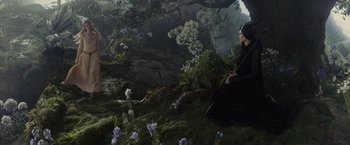 Movie still from “Maleficent” (2014), directed by Robert Stromberg – A woman sitting on a rock in a forest; Wide shot, High angle