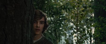 Movie still from “Maleficent” (2014), directed by Robert Stromberg – A young man standing next to a tree in the woods; Close Up shot, Over the shoulder angle