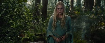 Movie still from “Maleficent” (2014), directed by Robert Stromberg – A beautiful blonde woman standing in the woods; Medium shot, Over the shoulder angle