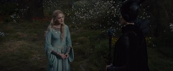 Movie still from “Maleficent” (2014), directed by Robert Stromberg – A woman in a blue dress talking to a man in a black suit; Medium shot, Over the shoulder angle