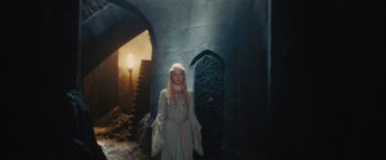 Movie still from “Maleficent” (2014), directed by Robert Stromberg – A young girl in a costume standing next to a stone wall; Wide shot, High angle