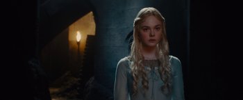 Movie still from “Maleficent” (2014), directed by Robert Stromberg – A woman with long blonde hair standing in front of a brick wall; Medium shot, Over the shoulder angle