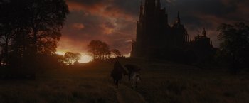 Movie still from “Maleficent” (2014), directed by Robert Stromberg – Two people riding horses in front of a castle at sunset; Extreme Wide shot, Low angle