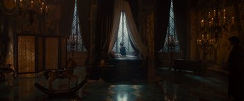 Movie still from “Maleficent” (2014), directed by Robert Stromberg – A person sitting in front of an open window in a room; Wide shot, High angle