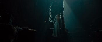 Movie still from “Maleficent” (2014), directed by Robert Stromberg – A woman in a blue dress standing on a staircase; Wide shot, Low angle