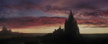 Movie still from “Maleficent” (2014), directed by Robert Stromberg – A castle is silhouetted against the sky at sunset; Extreme Wide shot, Low angle