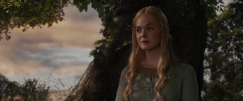 Movie still from “Maleficent” (2014), directed by Robert Stromberg – A young woman standing next to a large tree; Close Up shot, Low angle