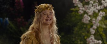 Movie still from “Maleficent” (2014), directed by Robert Stromberg – A woman with long blonde hair wearing a gold crown; Close Up shot, Low angle