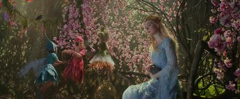 Movie still from “Maleficent: Mistress of Evil” (2019), directed by Joachim Rønning – A woman in a blue dress sitting in front of a tree; Wide shot, High angle