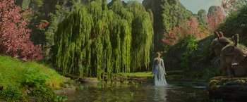Movie still from “Maleficent: Mistress of Evil” (2019), directed by Joachim Rønning – A woman standing in the water next to a tree; Extreme Wide shot, High angle