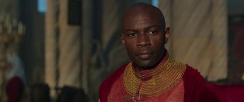 Movie still from “Maleficent: Mistress of Evil” (2019), directed by Joachim Rønning – A man in a red and gold outfit with a beard; Close Up shot, Over the shoulder angle