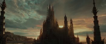 Movie still from “Maleficent: Mistress of Evil” (2019), directed by Joachim Rønning – The sun is setting behind a castle like building; Extreme Wide shot, Low angle