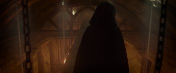 Movie still from “Maleficent: Mistress of Evil” (2019), directed by Joachim Rønning – A person wearing a hooded cloak standing in a dark room; Wide shot, Low angle