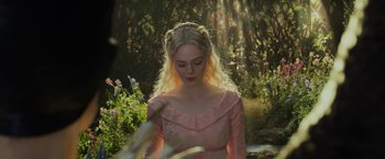 Movie still from “Maleficent: Mistress of Evil” (2019), directed by Joachim Rønning – A woman in a pink dress standing in a forest; Close Up shot, Over the shoulder angle
