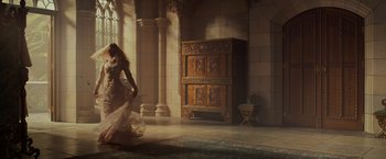 Movie still from “Maleficent: Mistress of Evil” (2019), directed by Joachim Rønning – A woman in a white dress in front of an ornate wooden cabinet; Wide shot, Low angle