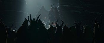 Movie still from “Maleficent: Mistress of Evil” (2019), directed by Joachim Rønning – A group of people in a dark room with horns on their heads; Wide shot, High angle