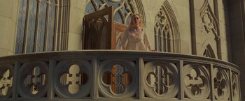 Movie still from “Maleficent: Mistress of Evil” (2019), directed by Joachim Rønning – A woman standing on top of a railing in front of a building; Wide shot, Low angle
