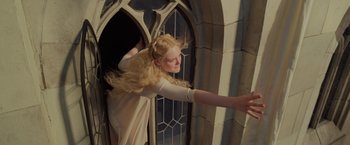 Movie still from “Maleficent: Mistress of Evil” (2019), directed by Joachim Rønning – A woman with long blonde hair is in front of a window; Medium shot, Low angle