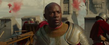 Movie still from “Maleficent: Mistress of Evil” (2019), directed by Joachim Rønning – A man wearing a chain mail armor and a red scarf; Close Up shot, Over the shoulder angle