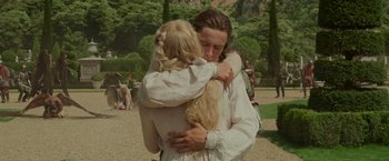 Movie still from “Maleficent: Mistress of Evil” (2019), directed by Joachim Rønning – A man and a woman hugging each other in a park; Medium shot, Low angle