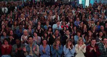 A large group of people sitting and clapping in a room