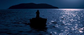 Movie still from “Mamma Mia!” (2008), directed by Phyllida Lloyd – A person sitting on a boat in the middle of the night; Extreme Wide shot, Low angle