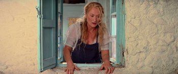 Movie still from “Mamma Mia!” (2008), directed by Phyllida Lloyd – A woman leaning against a window sill looking out of the window; Medium shot, Low angle