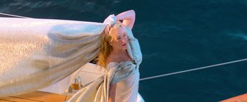 Movie still from “Mamma Mia!” (2008), directed by Phyllida Lloyd – A woman in a white dress standing on a sailboat in the ocean; Medium shot, Low angle