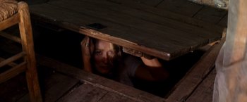 Movie still from “Mamma Mia!” (2008), directed by Phyllida Lloyd – A woman peeking out from under a wooden structure; Medium shot, Overhead angle