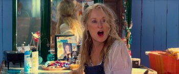 Movie still from “Mamma Mia!” (2008), directed by Phyllida Lloyd – A woman with long blonde hair is making a funny face; Close Up shot, Over the shoulder angle