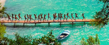 Movie still from “Mamma Mia!” (2008), directed by Phyllida Lloyd – A group of people walking across a bridge; Extreme Wide shot, High angle