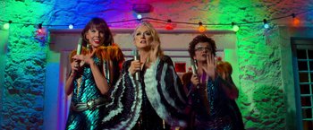 Movie still from “Mamma Mia!” (2008), directed by Phyllida Lloyd – A group of women singing into microphones in front of lights; Medium shot, Overhead angle