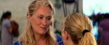 Movie still from “Mamma Mia!” (2008), directed by Phyllida Lloyd – A woman talking to another woman in front of a table; Close Up shot, Over the shoulder angle