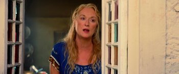 Movie still from “Mamma Mia!” (2008), directed by Phyllida Lloyd – A woman standing in front of an open window; Close Up shot, Over the shoulder angle