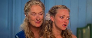Movie still from “Mamma Mia!” (2008), directed by Phyllida Lloyd – Two women are posing for a picture together; Close Up shot, Over the shoulder angle