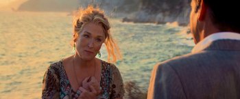 Movie still from “Mamma Mia!” (2008), directed by Phyllida Lloyd – A woman sitting next to a body of water; Close Up shot, Over the shoulder angle