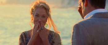 Movie still from “Mamma Mia!” (2008), directed by Phyllida Lloyd – A beautiful woman with blond hair and a tattoo covering her mouth; Close Up shot, Over the shoulder angle