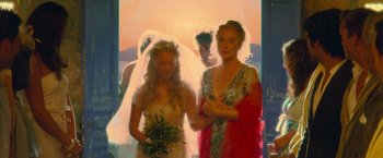 Movie still from “Mamma Mia!” (2008), directed by Phyllida Lloyd – Two women and a man are standing in front of a sunset; Medium shot, Over the shoulder angle