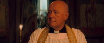 Movie still from “Mamma Mia!” (2008), directed by Phyllida Lloyd – A man in a priest's outfit looking at the camera; Close Up shot, Low angle